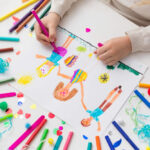 Child drawing colorful family portrait with markers.