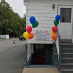 Colorful balloons decorate entrance to a basement sales event.