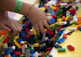 Child's hand reaching for colorful LEGO bricks in a pile.