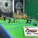 LEGO Hogwarts castle and characters assembled on a green table.